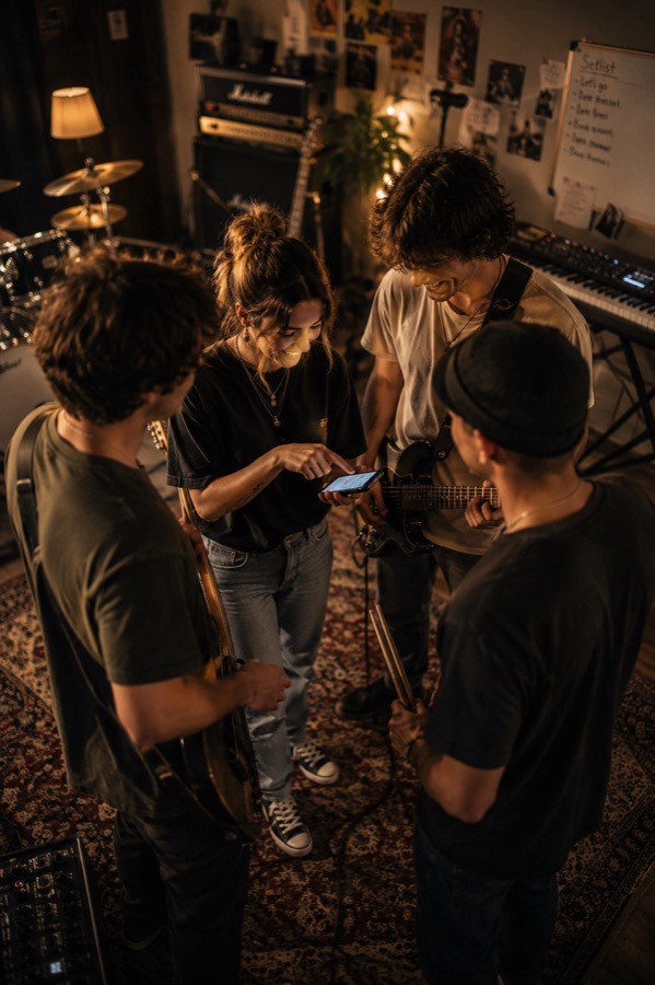 Band schaut gemeinsam auf ein Smartphone im Proberaum